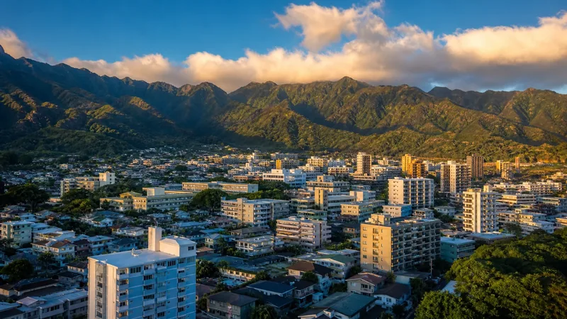 Dense urban island city streets of low and mid-rise buildings with green volcanic ridges behind, morning light, Honolulu Business License (Oahu)
